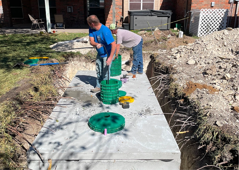Two men assembling green septic covers
